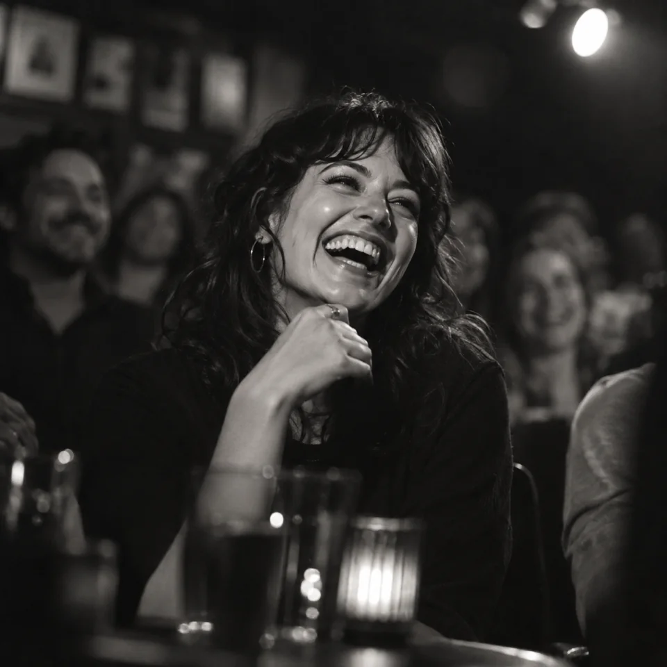 A woman caught in a spontaneous laugh at a comedy club